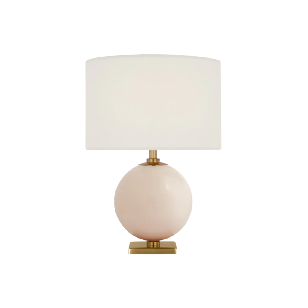 Elsie Cordless Accent Lamp by Kate Spade New York, featuring a reverse-painted glass body in soft blush or cream tones, suspended between warm brass accents, and topped with a natural linen shade—combining portability with sophisticated design.​